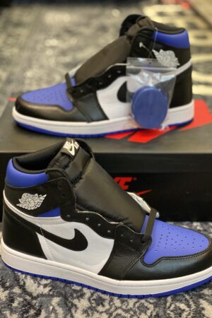 : A pair of white and blue Travis Scott x Fragment Air Jordan 1 sneakers resting on a grey patterned rug.