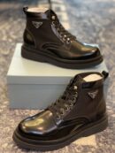 Black Prada combat boots made of leather and nylon with the silver triangle logo sitting on a light blue box.