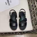 Top-down view of Berluti Cross sandals featuring a forest green patina leather strap, black Scritto engraved straps, and a thick black comfort sole on a light surface.