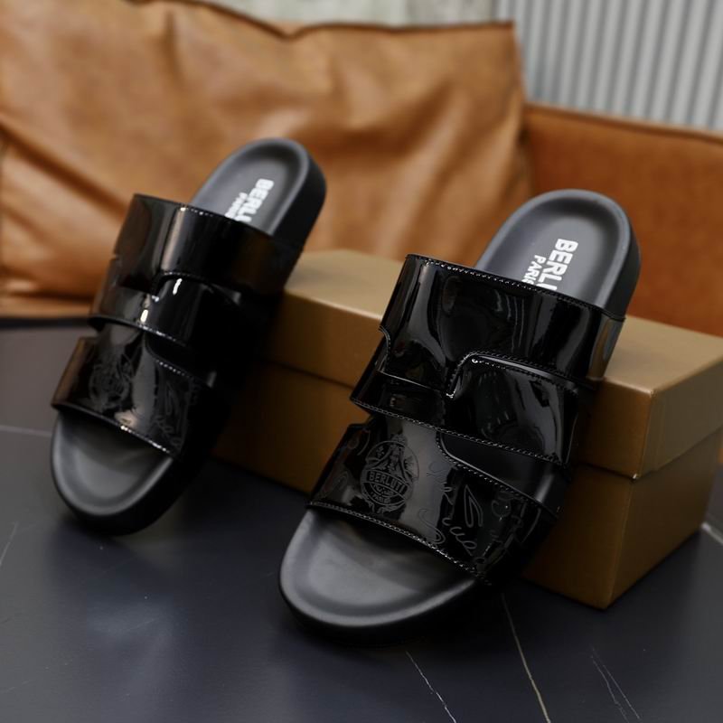 Top-down view of black patent leather Berluti Scritto sandals with a unique H-strap design and black contoured soles displayed on a grey table.
