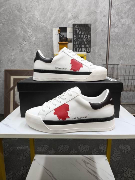 A pair of white leather Dsquared2 low-top sneakers with a red maple leaf patch on the side and a black heel tab, displayed on a marble surface.