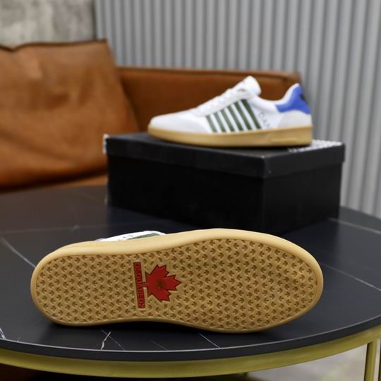 DSQUARED2 Boxer low-top sneakers in white leather with olive green side stripes, light gray suede toe caps, and a royal blue heel tab, shown on a dark table.