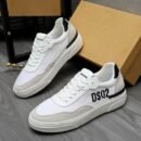 A pair of DSQUARED2 Run low-top sneakers in white leather and grey suede, featuring a prominent black "DSQ2" logo on the side and a black heel tab, leaning against a cardboard box.