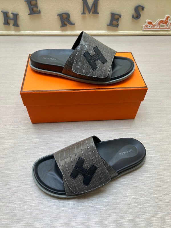 Grey croco-embossed Hermès Izmir sandals with black H logo patches and black footbeds shown with an orange box.