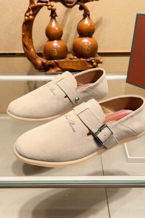 Pair of sand-colored suede Loro Piana Summer Charms Walk loafers featuring a buckle strap closure and flexible soles displayed on a glass shelf.