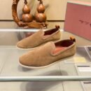 Pair of caramel brown suede Loro Piana 360 LP Flexy Walk sneakers with leather heel tabs displayed on a glass shelf.