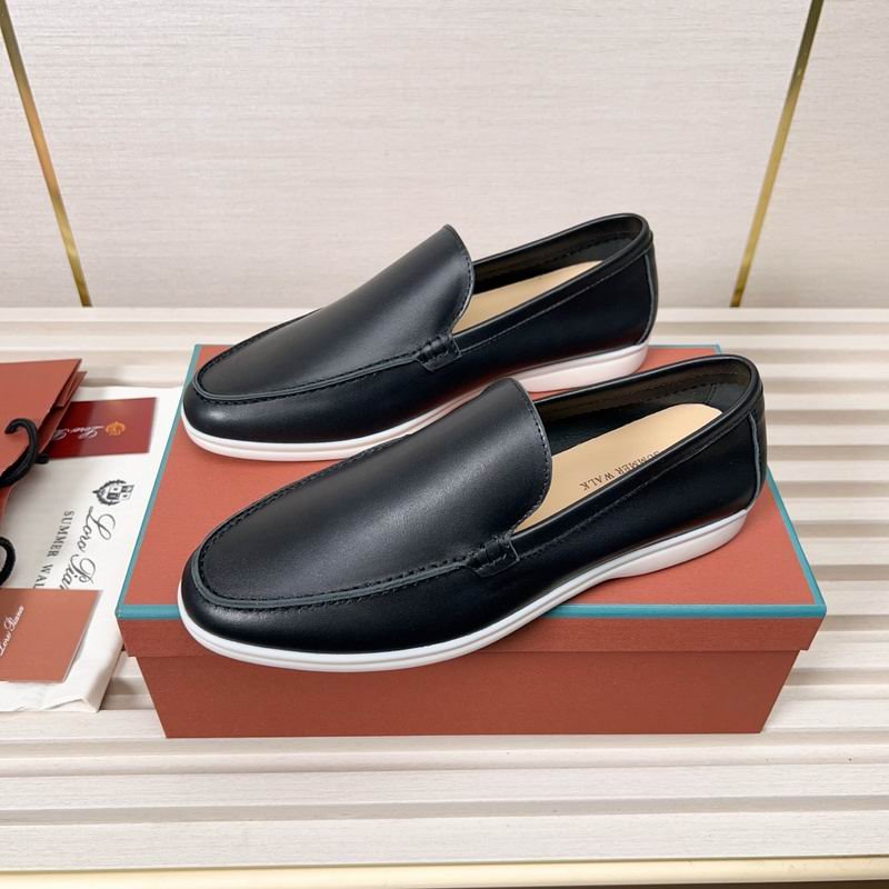Pair of black leather Loro Piana Summer Walk loafers with white soles resting on a light-colored ribbed surface next to original orange packaging.