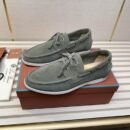 A pair of sage green suede Loro Piana Summer Walk loafers with white soles resting on a white slatted display surface.
