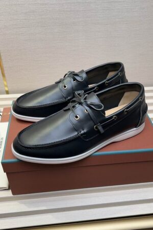A pair of black leather Loro Piana Summer Walk loafers with white soles sitting on a brown designer shoe bo