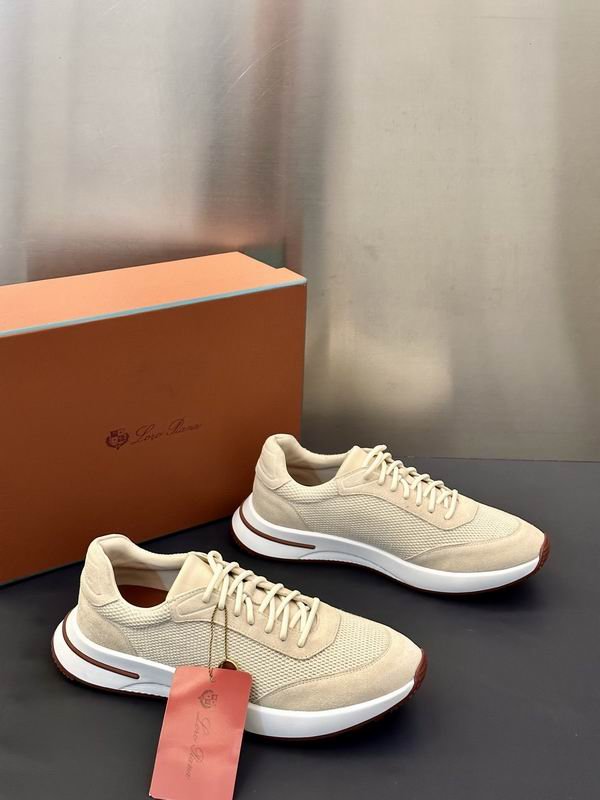 A pair of premium men's beige knit and suede sneakers with white rubber soles displayed on a dark surface next to an orange luxury shoe box.